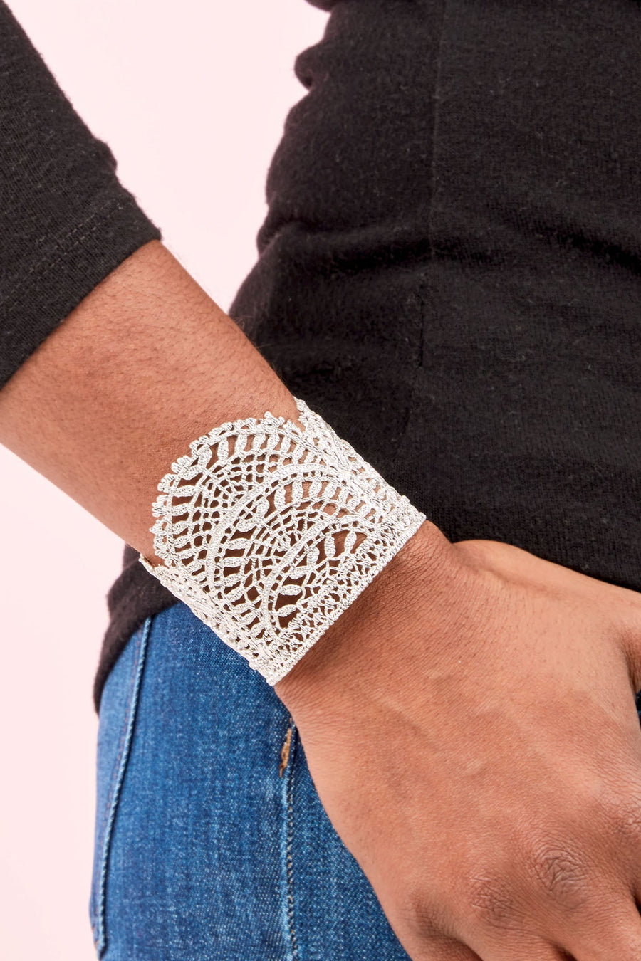 Person wearing a silver bracelet on a plain background